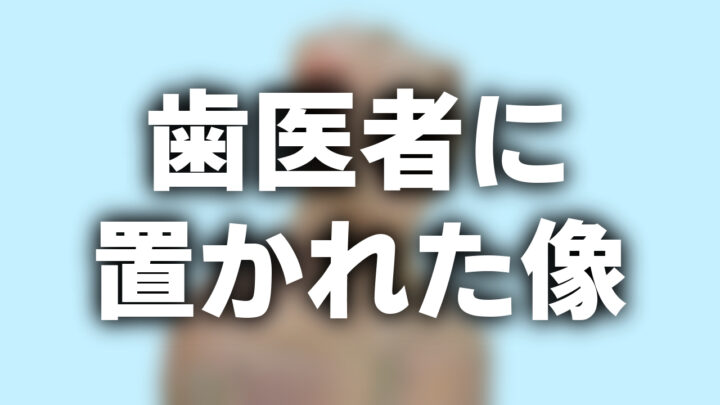 「歯医者に置かれた像」という影付きの白文字が、水色の背景とぼかされた胸像の画像の上に書かれている。